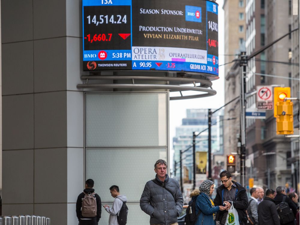  TORONTO, ONT.: March 9, 2020 — People walk by a screen displaying devalued stocks and the TSX outside of Bank of Montreal at King and Bay Streets. Toronto, Ont., March 9, 2020. (Nick Kozak for Postmedia News).
