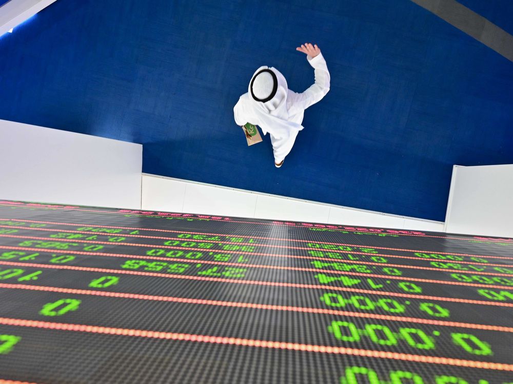  A trader passes under a stock display board at the Dubai Stock Exchange in the United Arab Emirates, on March 8.