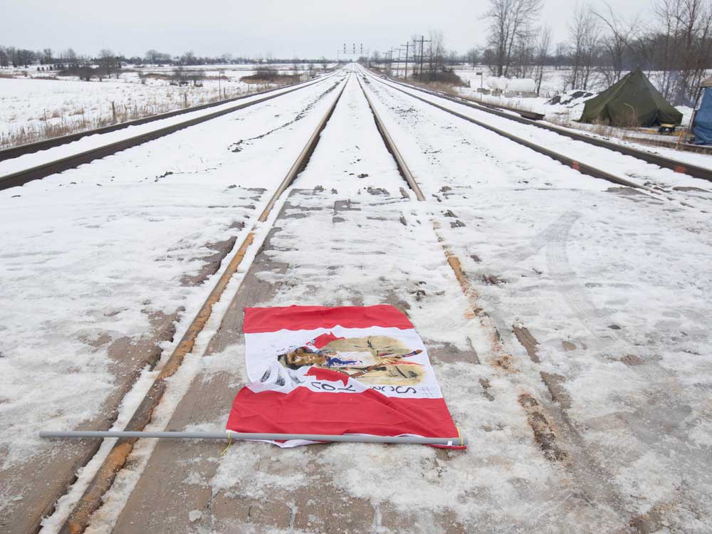  A Canadian flag with Indigenous symbols on it lays across the CN train tracks in Tyendinaga Mohawk Territory, near Belleville, Ont.