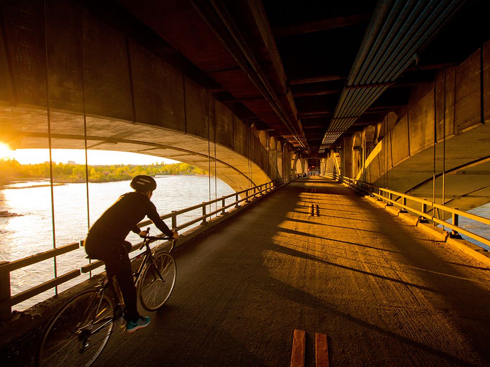  A cyclist crosses the lower deck of the centre street bridge as the setting sun lights up the arches of the 104 year-old bridge on Wednesday, May 27, 2020.