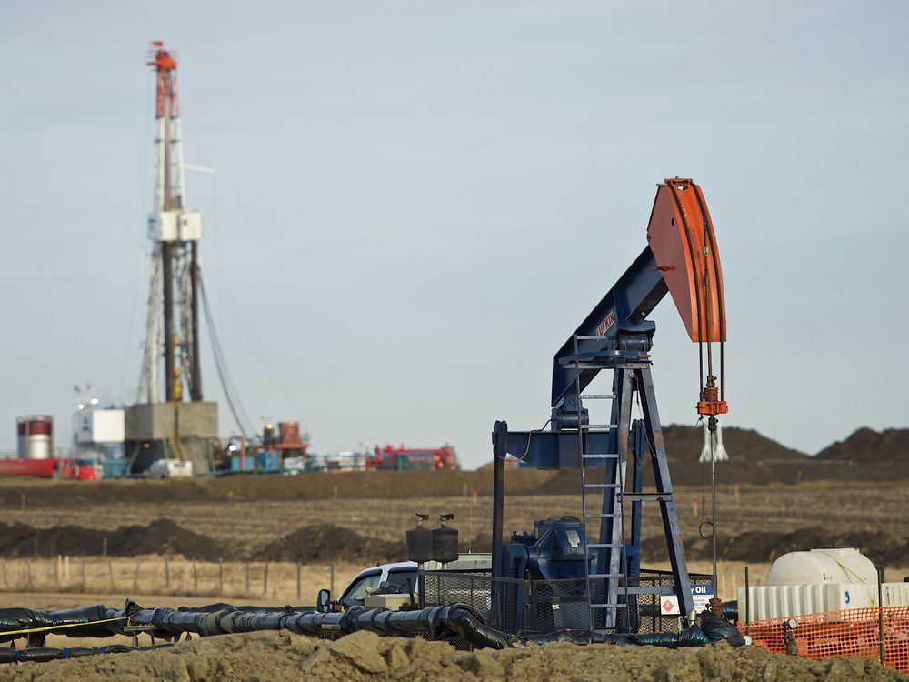  Pumpjack works in the foreground with a drilling rig on a Husky Oil site east of Bruderheim, Alberta.