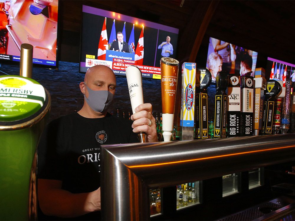  General manager Jason Reeb of The Cat ‘n Fiddle Pub pours a beer as Premier Jason Kenney announces new restrictions in Calgary on Tuesday, Dec. 8, 2020.