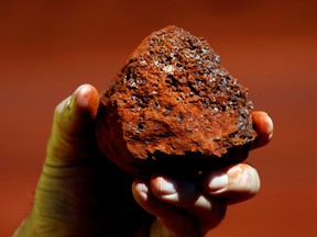 A miner holds a lump of iron ore in Australia.