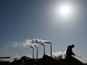 A worker uses a torch to cut steel pipes near the coal-powered Datang International Zhangjiakou Power Station at Zhangjiakou, one of the host cities for the 2022 Winter Olympics, in China's northern Hebei province.