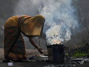 A woman burns coal for domestic use at Singrauli in India's Madhya Pradesh state on November 18, 2021.