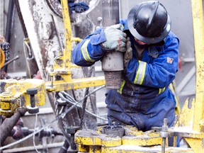 An Ensign roughneck working for Nexen, positions a section of pipe to the drilling hole in this file photo.