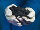 An oilsands worker holds a handful of bitumen. Energy companies here are focused on returning money to investors, rather than investing in long-term growth.