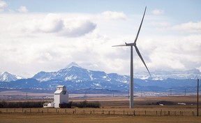 A wind turbine towers over a grain elevator near Pincher Creek.