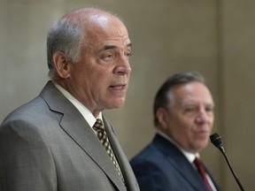 Quebec Economy and Innovation Minister Pierre Fitzgibbon responds to reporters questions as Quebec Premier Francois Legault, right, looks on at the legislature in Quebec City.