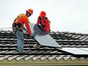 Workers install solar panels on a roof. Spain's rooftop industry is experiencing a boom as the price of power more than doubles in the wake of the Russian invasion of Ukraine.