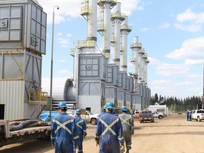 Employees at the Cenovus Christina Lake oilsands facility, located south of Fort McMurray, walk past steam generators as they begin their shift in this May 2012 file photo.