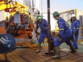 Trainees Dan Brook and Bradley Williams are directed by instructor Clint Dyck while training to lay down drill pipe on a rig floor, at Precision Drilling in Nisku, Alta., on January 20, 2016.